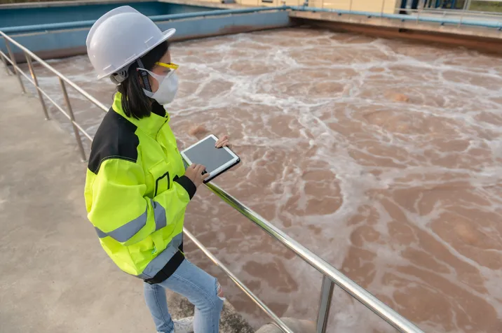 person in hard hat standing over water
