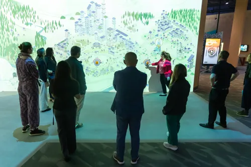 Katrina Stevens, President & CEO of The Tech Interactive, demonstrates the museum's Connections Wall in its Solve for Earth gallery during a visit from ASML community engagement executives.