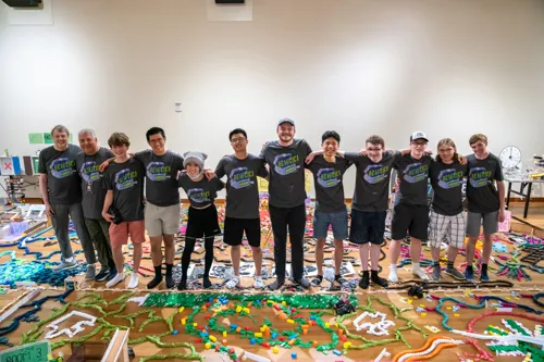 The Reactica team after the 2025 Tech Topple at The Tech Interactive, surrounded by thousands of dominoes and the remains of their epic chain-reaction build.